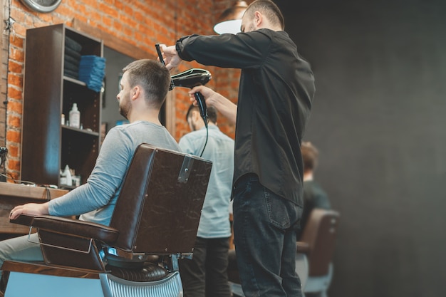 El maestro de Barbeshop le sopla el cabello y la barba al cliente con un secador de pelo. Lavado de cabello y barbas. Peluquero para hombres.