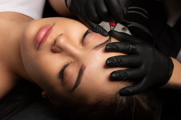 Foto maestro de belleza haciendo maquillaje permanente con una máquina