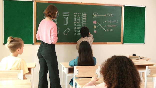 El maestro chequeando la tarea linda del estudiante mientras explica la idea en la pedagogía de la clase