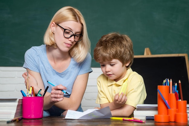 Maestro de concepto de niño de educación y aprendizaje de la escuela primaria que ayuda a un niño con una gran lección ...