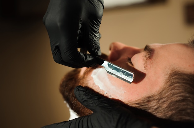 Maestro corta el pelo y la barba de los hombres en la barbería