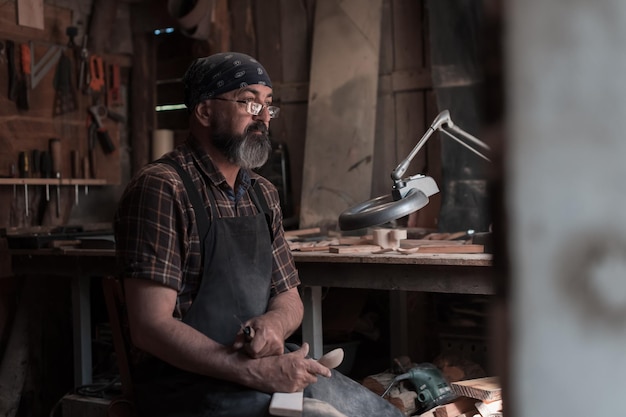 Maestro de cucharas en su taller con productos y herramientas de madera. foto de alta calidad