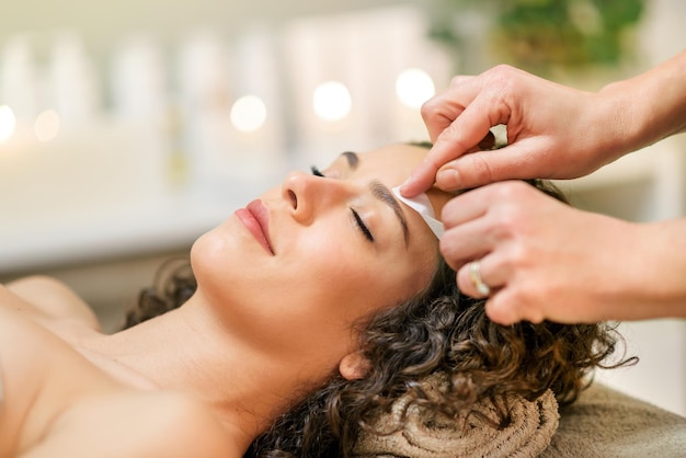 Maestro depilación de cejas de cliente relajado en estudio de belleza