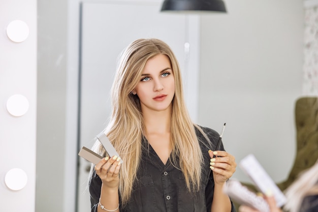 Maestro de diseño de cejas joven hermosa mujer con una sonrisa y herramientas profesionales en manos de un salón de belleza