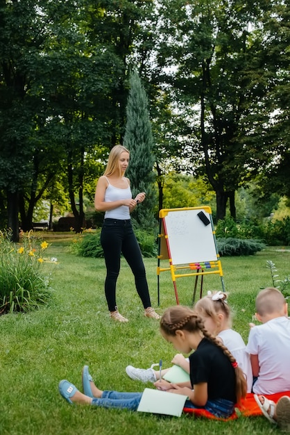 El maestro enseña a una clase de niños en un parque al aire libre