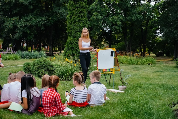 Un maestro enseña a una clase de niños en un parque al aire libre