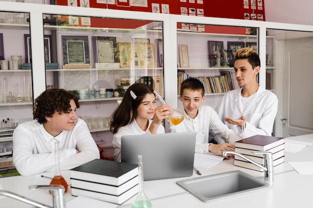 El maestro de escuela da una lección de química a los niños en un laboratorio con frascos con líquidos para experimentos Concepto de educación Lección grupal de compañeros de clase en la lección de química