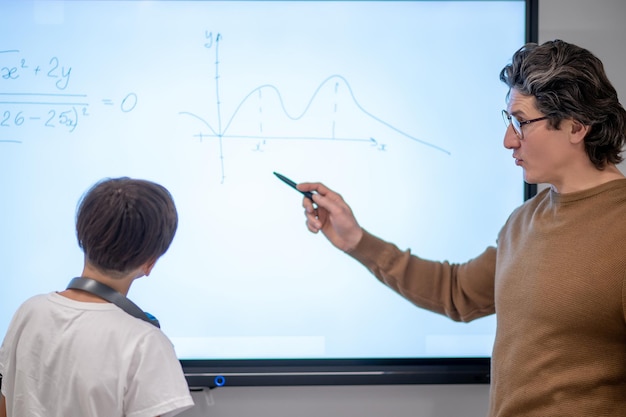 Un maestro de escuela explicando un nuevo tema en la lección de matemáticas