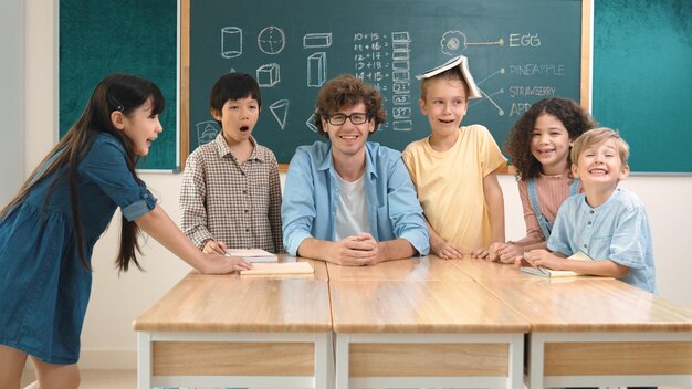 El maestro y el estudiante miran a la cámara mientras el niño está de pie en la tabla de pedagogía