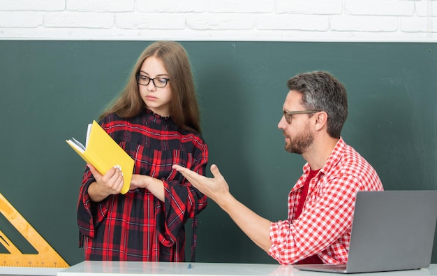 El maestro explica la lección a los niños de la escuela primaria aprendiendo a hacer la tarea escribiendo y r