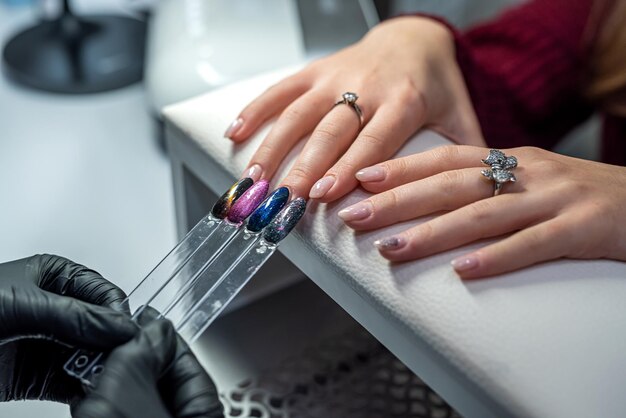 Un maestro de extensión de uñas profesional selecciona el color para su cliente durante la epidemia. Concepto de manicura