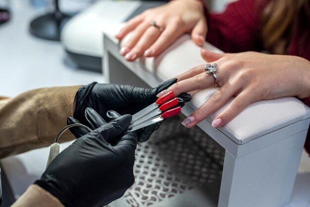 Un maestro de extensión de uñas profesional selecciona un color para su cliente durante una epidemia