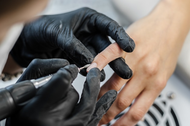 El maestro hace manicura de hardware en el salón de belleza.