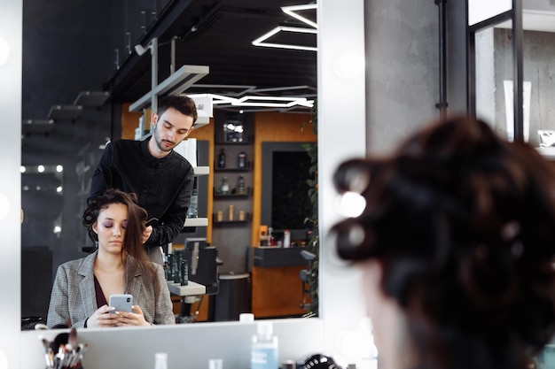 Foto el maestro hace el peinado en un salón de belleza, una mujer joven que se prepara para una cita con una foto de alta calidad.