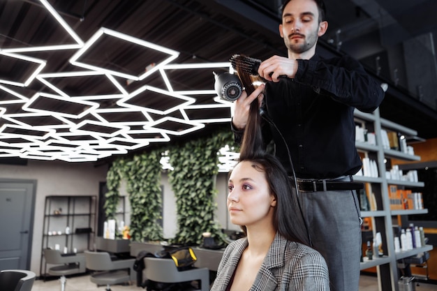 Foto el maestro hace el peinado en un salón de belleza, una mujer joven que se prepara para una cita con una foto de alta calidad.