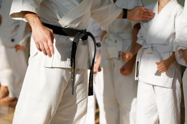 Maestro de Karate en un kimono blanco y con un cinturón negro se para frente a la formación de su