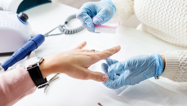 Maestro de manicura con un cepillo para limpiar el polvo después de quitar el esmalte en gel