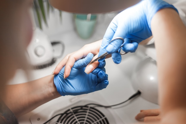 El maestro de manicura corta la cutícula con unas tijeras