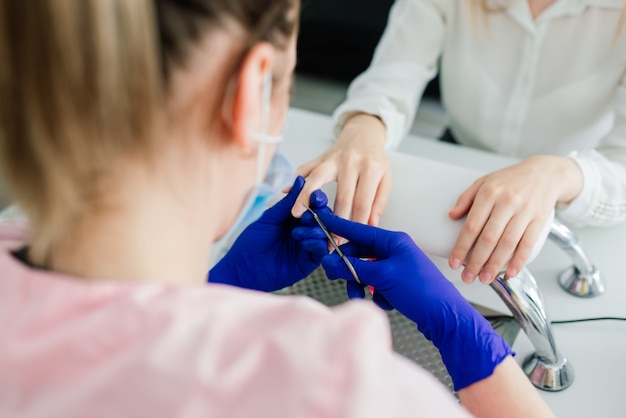 Maestro de manicura femenina en un salón de belleza trabaja con las manos del cliente