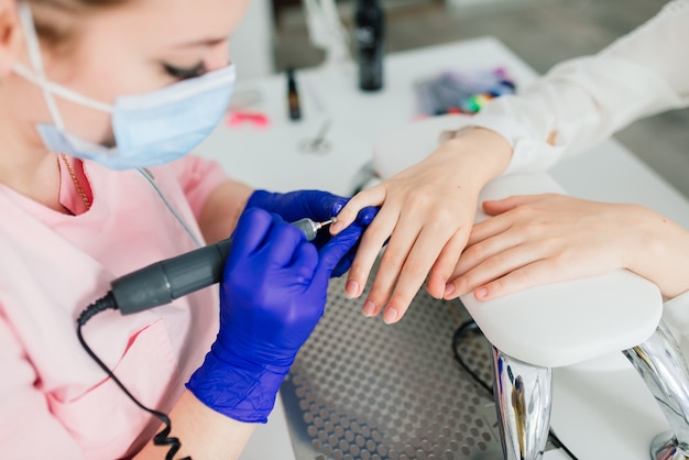 Maestro de manicura femenina en un salón de belleza trabaja con las manos del cliente