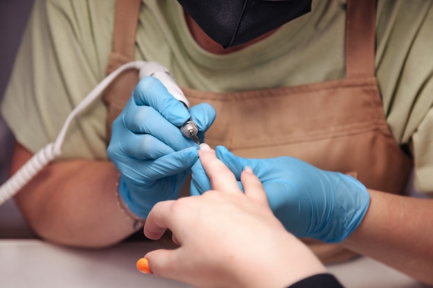 Maestro de manicura hace que las uñas sean una mujer joven y bonita en un salón de belleza. Atención al cliente en salón interior para crear una imagen sorprendente. Asistente de creación de obra. Concepto de satisfacción de la medida. Copia espacio