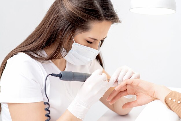 Foto maestro de manicura haciendo manicura con máquina herramienta eléctrica.