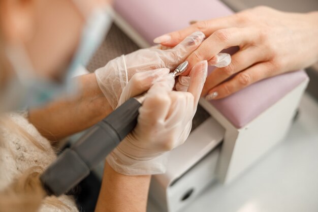 Maestro de manicura profesional está haciendo uñas para el cliente en el salón de belleza