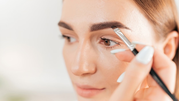 El maestro de maquillaje maquilla a un cliente. Pintura de cejas