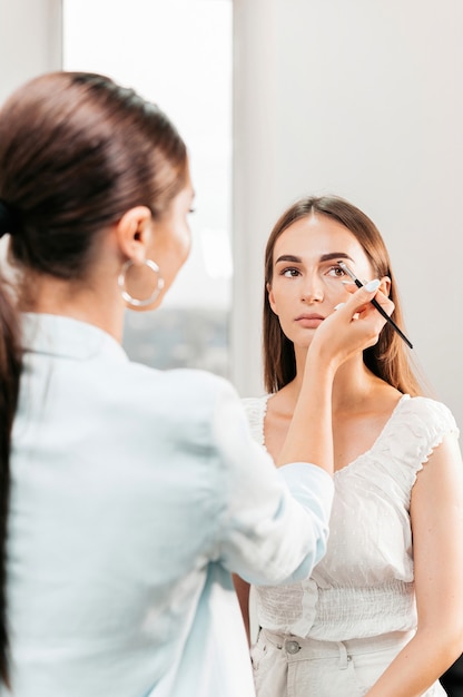 El maestro de maquillaje maquilla a un cliente. Pintura de cejas