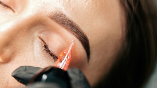 El maestro de maquillaje realiza el procedimiento de maquillaje permanente de cejas para el cliente.