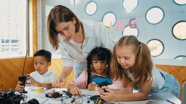 Foto el maestro mirando a los niños mientras el estudiante diverso mira la pantalla erudición