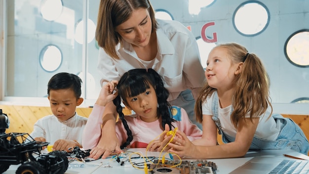 El maestro mirando a los niños mientras el estudiante diverso mira la pantalla Erudición