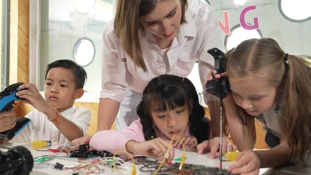 El maestro mirando a los niños mientras el estudiante diverso mira la pantalla Erudición