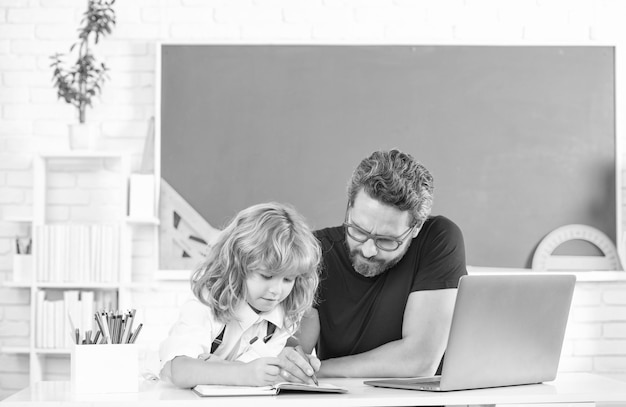 Foto el maestro y el niño estudian en el aula con la paternidad de la computadora portátil