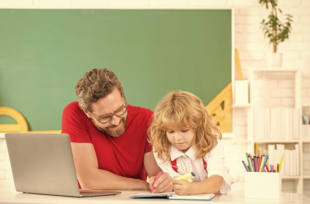 El maestro y el niño estudian en el aula con la paternidad de la computadora portátil