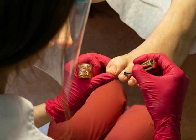 El maestro de pedicura aplica aceite hidratante a las cutículas.