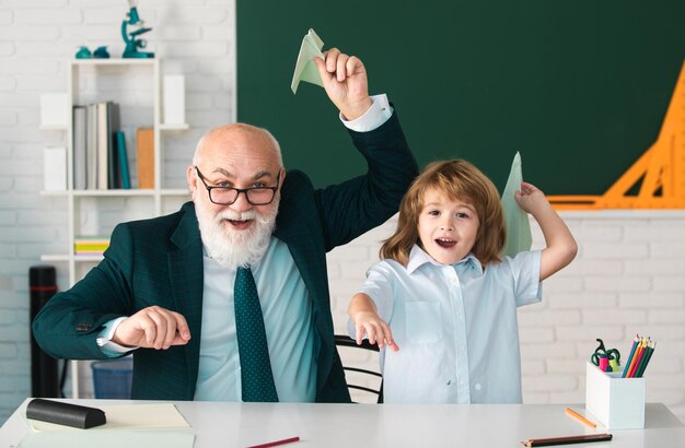 El maestro principal o el abuelo y el alumno del colegio sostienen un avión de papel en el aula de la escuela Lección divertida privada