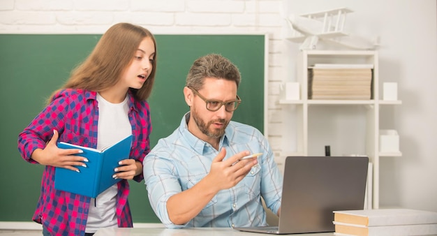 El maestro privado y el niño sostienen el cuaderno. La familia ayuda a papá e hija a usar el cuaderno.