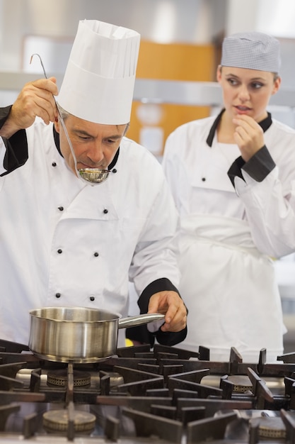 Maestro probando la sopa de sus alumnos con ella mirando ansiosamente