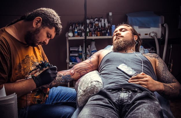 El maestro del tatuaje hace dibujos de tatuajes en el salón de tatuajes.