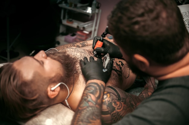 El maestro del tatuaje hace fotos de tatuajes en el salón de tatuajes