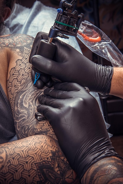 Maestro del tatuaje haciendo tatuajes en el salón de tatuajes