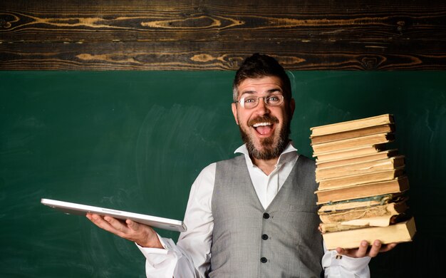 El maestro tiene un libro de texto tradicional y una lectura de libros electrónicos.