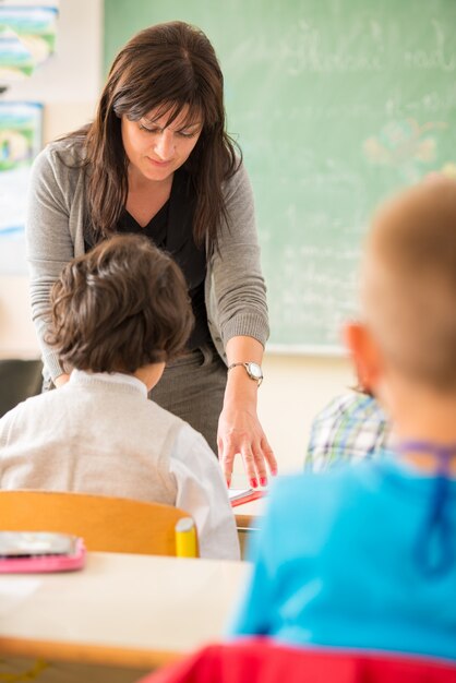 Foto maestro trabajando con niños en el aula de la escuela