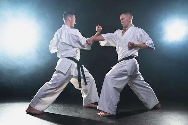 Maestros de artes marciales en fondo oscuro luchadores de hombres fuertes en kimono blanco para artes marciales de karate