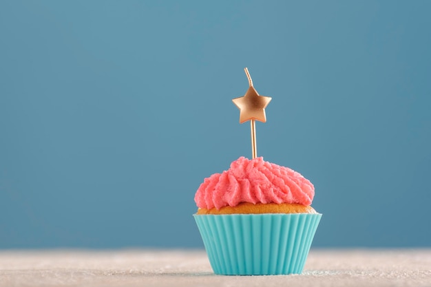 Magdalena casera con velas en forma de estrella. Muffin festivo sobre fondo azul. Copie el espacio.