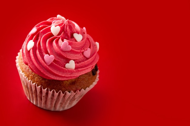 Magdalena decorada con corazones de azúcar para el día de San Valentín sobre fondo rojo.