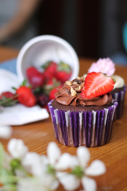 Foto magdalena dulce en la mesa de madera con fresas y flores.