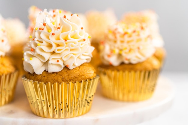 Magdalena de especias de calabaza con crema de mantequilla italiana y chispas en un soporte para pasteles.