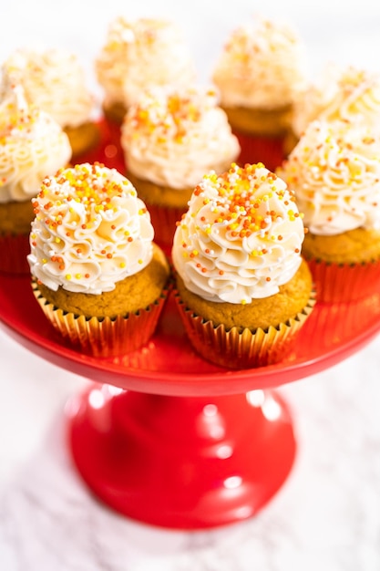 Magdalena de especias de calabaza con crema de mantequilla italiana y chispas en un soporte para pasteles.